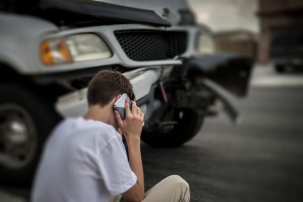 young man calling 911 after a car accident