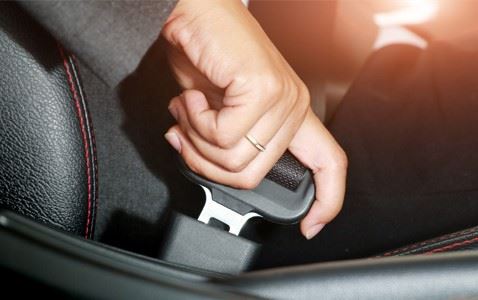 person buckling their seat belt in car