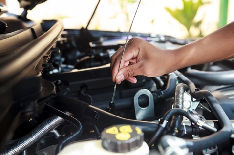 person checking their car's engine oil levels