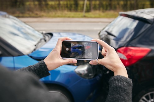 woman taking photos of her car after crash