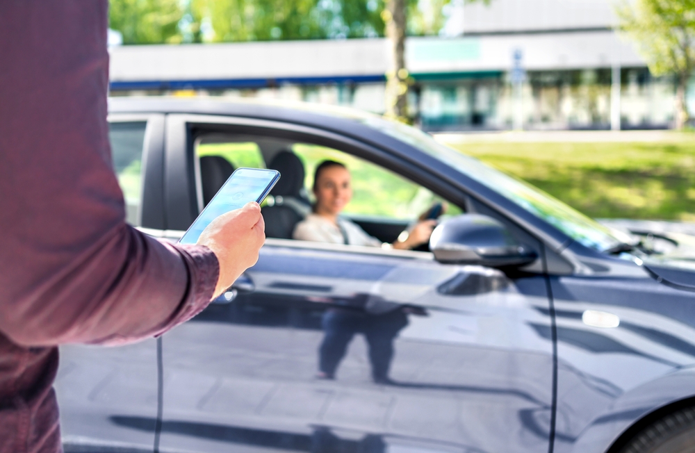 Rideshare driver arriving to pick up a passenger while a person checks a phone